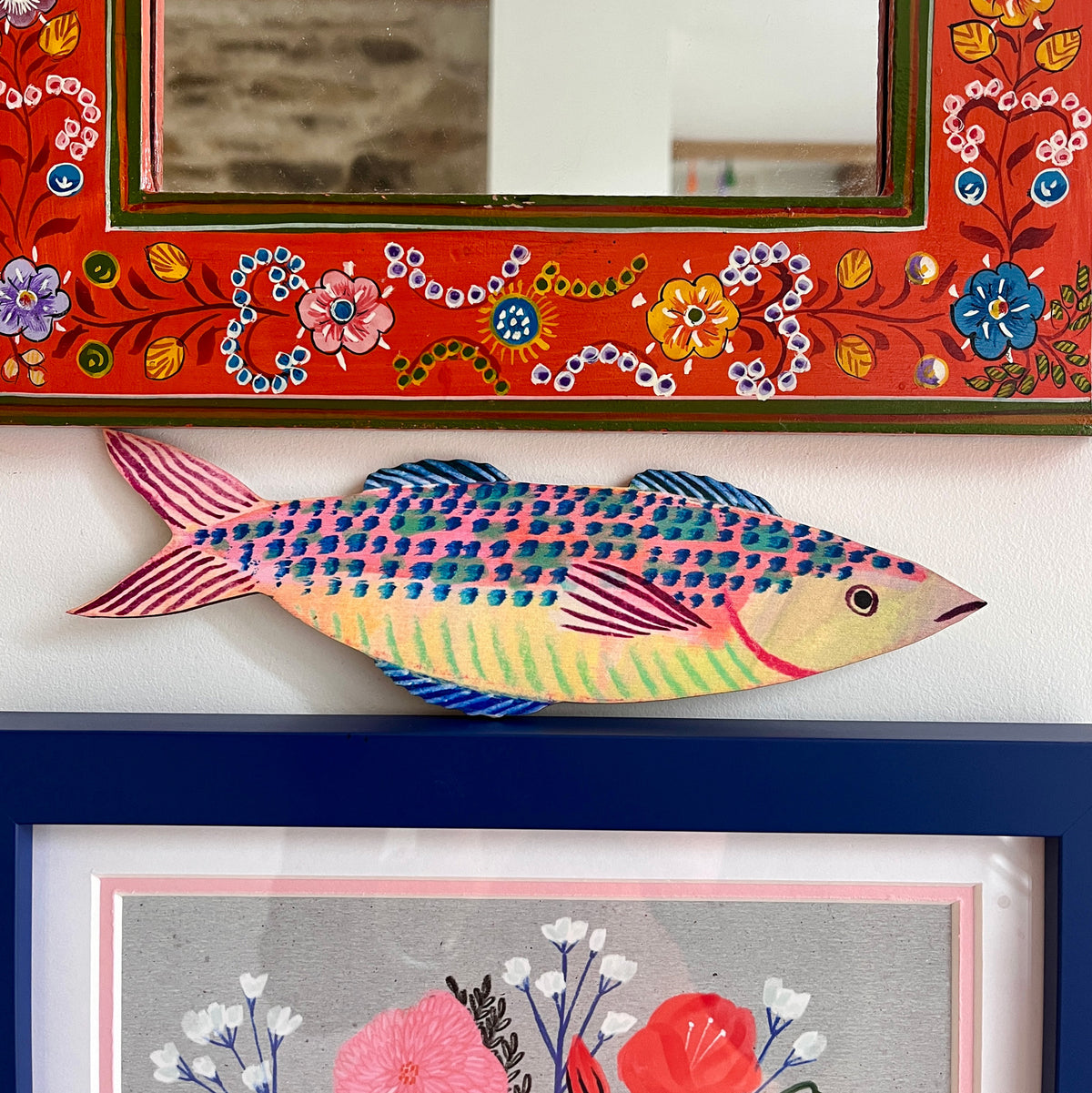 Colourful mackerel fish decoration by Lee Foster-Wilson displayed between colourful frames